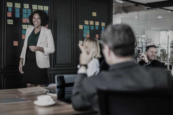 attorneys in meeting man sitting and pointing at a standing smiling woman